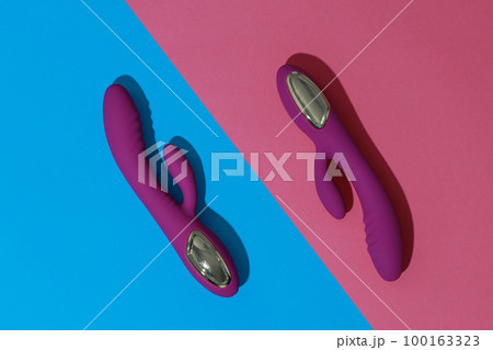 Two violet dildo vibrators on colored background. Sex toy for adult. Sex shop concept 100163323