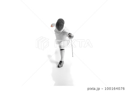 Full-length portrait of sportive man, professional fencer in fencing costume and protective helmet mask in motion isolated on white studio background. 100164076