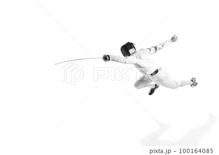 Full-length portrait of sportive man, professional fencer in fencing costume and protective helmet mask in motion isolated on white studio background. 100164085