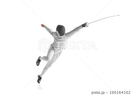 Professional male fencer in fencing costume training with sword isolated on white studio background. Concept of sport, competition, professional skills, achievements 100164102