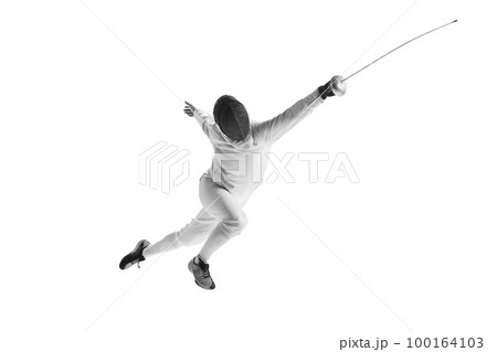 Full-length portrait of sportive man, professional fencer in fencing costume and protective helmet mask in motion isolated on white studio background. 100164103