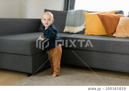 Caucasian baby newborn infant making first steps. Cute toddler kid child son boy learning walking creeping on living room copy space. Childcare and childhood concept 100165829