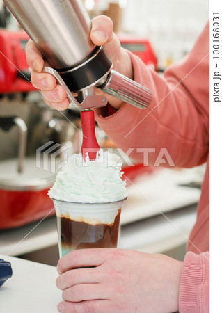 the barista decorates the cocktail with whipped cream and colored sprinkles the barista decorates the cocktail with whipped cream and colored sprinkles 100168031