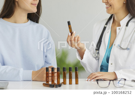 Doctor giving herbal essential oil flask inhaler female patient Doctor giving herbal essential oil flask inhaler female patient 100168252