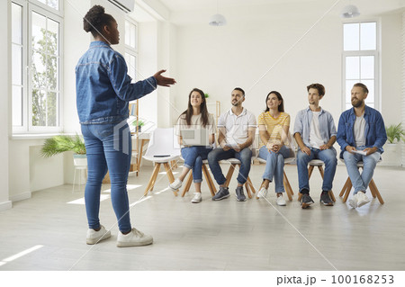 Team of young workers listening to an African American business speaker and coach Team of young workers listening to an African American business speaker and coach 100168253