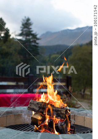 burning bonfire in a fire pit in the evening light and mountain views. burning bonfire in a fire pit in the evening light and mountain views. 100171542