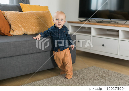 Caucasian baby newborn infant making first steps. Cute toddler kid child son boy learning walking creeping on living room copy space. Childcare and childhood concept 100175994