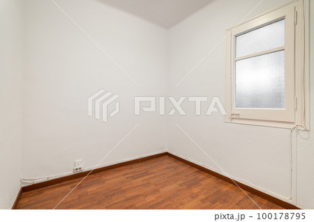 Empty room with laminate flooring, newly painted white walls and bright window with frosted glass. Repair and construction concept. Empty room with laminate flooring, newly painted white walls and bright window with frosted glass. Repair and construction concept. 100178795