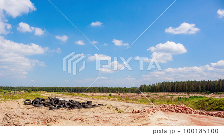 Environmental pollution. Used tires, broken bricks in the background of nature 100185100