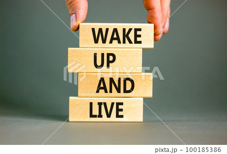 Wake up and live symbol. Concept words Wake up and live on wooden blocks. Beautiful grey table grey background. Businessman hand. Business lifestyle wake up and live concept. Copy space. 100185386