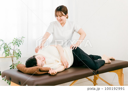 整骨院で骨盤矯正をする整体師・マッサージ師・セラピストの女性 整骨院で骨盤矯正をする整体師・マッサージ師・セラピストの女性 100192991