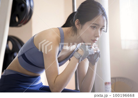 スポーツジムで休憩をする若い女性 100196668