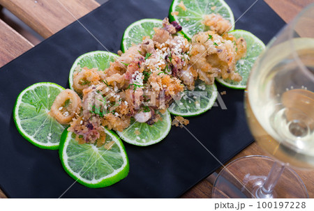Squid and cuttlefish tempura on lime slices with wine 100197228