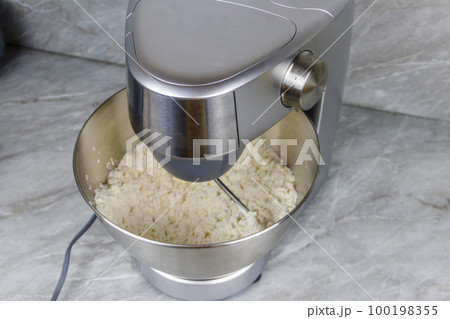 Kneading dough in the modern kitchen machine on a table Kneading dough in the modern kitchen machine on a table 100198355