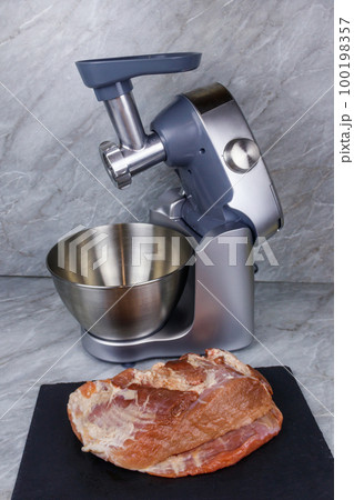 Electric eat grinder and fresh meat on kitchen table. Preparation of minced meat 100198357