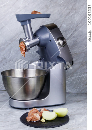 Electric eat grinder and fresh meat on kitchen table. Preparation of minced meat Electric eat grinder and fresh meat on kitchen table. Preparation of minced meat 100198358