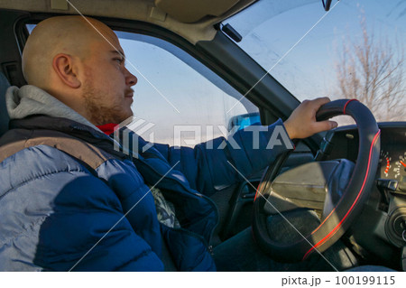 Young man driving a car on winter road. Inside view Young man driving a car on winter road. Inside view 100199115