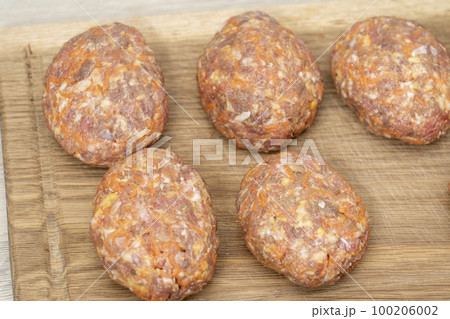 raw homemade meatballs on a massive board made of natural wood raw homemade meatballs on a massive board made of natural wood 100206002