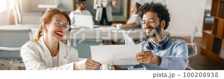 Two young diverse coworkers analyzing sales report while working together in the office Two young diverse coworkers analyzing sales report while working together in the office 100208938