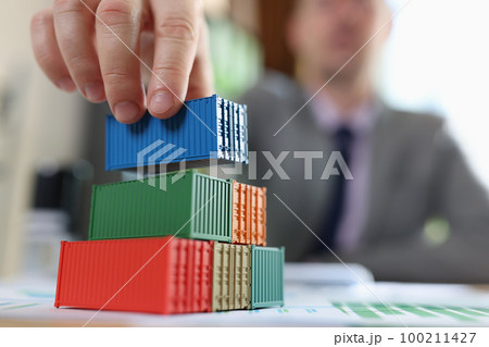 Business man arranging several cargo containers on his table with financial reports. 100211427