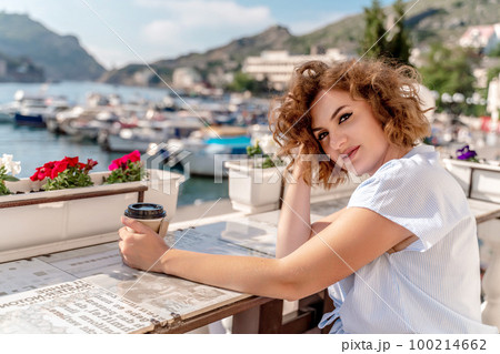 Happy beautiful woman drinking coffee with milk and having healthy breakfast in outdoor cafe in summer city in Europe. Happy beautiful woman drinking coffee with milk and having healthy breakfast in outdoor cafe in summer city in Europe. 100214662