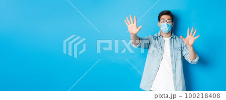 Concept of coronavirus, social distancing and pandemic. Man in medical glass cant see in foggy glasses, standing over blue background Concept of coronavirus, social distancing and pandemic. Man in medical glass cant see in foggy glasses, standing over blue background 100218408