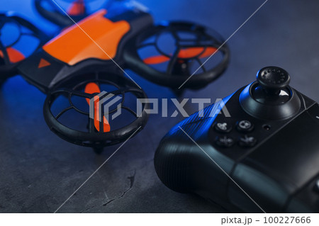 Gaming orange mini drone on a dark background with a joystick control Gaming orange mini drone on a dark background with a joystick control 100227666