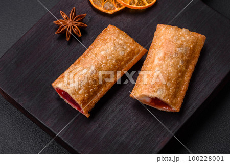 Delicious fresh crispy pie with cherry jam on a wooden cutting board 100228001