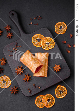 Delicious fresh crispy pie with cherry jam on a wooden cutting board 100228005