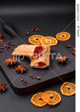Delicious fresh crispy pie with cherry jam on a wooden cutting board 100228006