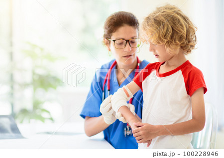 Child with arm injury. Kid with cast at clinic. 100228946
