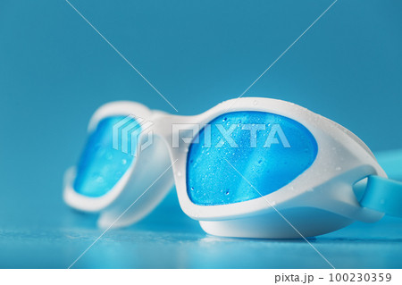 White swimming goggles on a blue background 100230359
