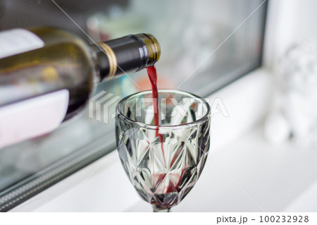 Red wine pouring from bottle. Wine glass with red wine. Alcohol drinks. Celebraion background. Wine from bottleneck. Bar background. Red wine pouring from bottle. Wine glass with red wine. Alcohol drinks. Celebraion background. Wine from bottleneck. Bar background. 100232928