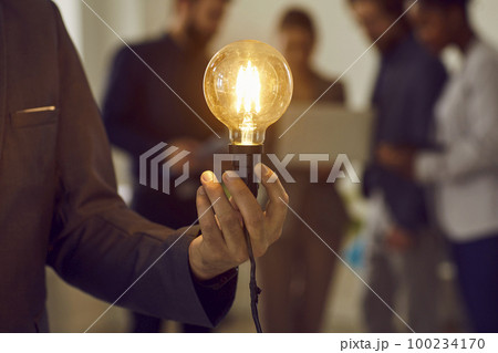 Glowing electric light bulb in hand of unknown smart and successful businessman dressed in suit. Glowing electric light bulb in hand of unknown smart and successful businessman dressed in suit. 100234170