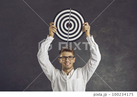 Happy young man holding shooting target to show concept of setting business goals Happy young man holding shooting target to show concept of setting business goals 100234175