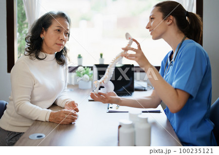 Portrait of a female doctor talking to an elderly patient about herniated disc deterioration from long hours of work Portrait of a female doctor talking to an elderly patient about herniated disc deterioration from long hours of work 100235121