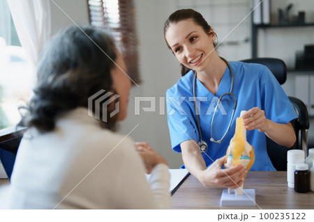 Portrait of a female doctor talking to an elderly patient about osteoarthritis 100235122