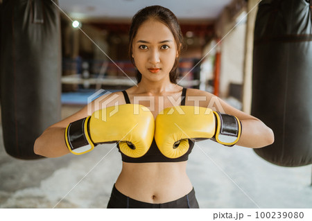 a female boxer put her boxing gloves together a female boxer put her boxing gloves together 100239080