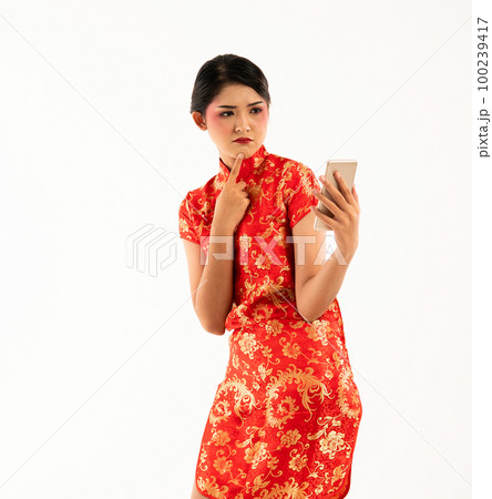 a beautiful woman in red cheongsam standing look at the phone a beautiful woman in red cheongsam standing look at the phone 100239417