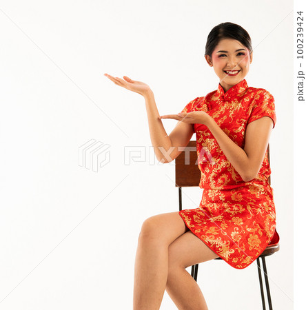asian woman in cheongsam sitting and pointed to her right side asian woman in cheongsam sitting and pointed to her right side 100239424