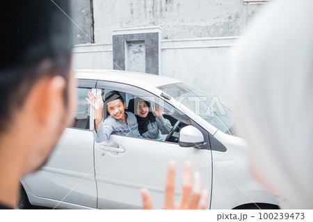 Asian Muslim couple meet by waving from car window Asian Muslim couple meet by waving from car window 100239473