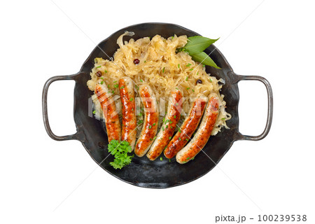 Fried Nuremberg sausages with sauerkraut served in an iron frying pan on white background 100239538