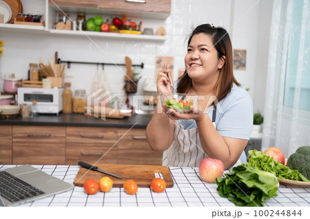 Asian Pregnant learn how to cook healthy meals from the Internet in kitchen, Fat women prepare a vegetable salad for diet food and lose weight. Concept of healthy eating Asian Pregnant learn how to cook healthy meals from the Internet in kitchen, Fat women prepare a vegetable salad for diet food and lose weight. Concept of healthy eating 100244844