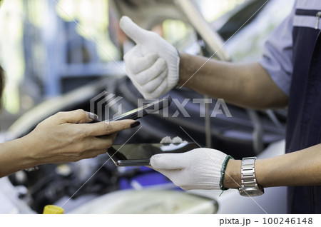 Asian women get contact numbers from Asian male auto mechanics after fixing the car engine problem and QR code scan to pay for fixing vehicle service. Car repair, and maintenance concept. 100246148
