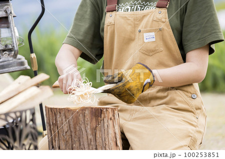 焚き火用にフェザースティックを作る若い女性　ソロキャンプイメージ 100253851