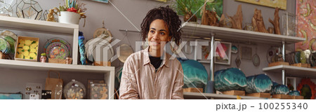 Smiling woman is packing handmade candles for selling in own home decor studio 100255340