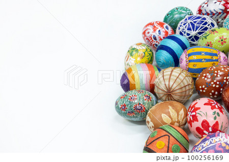 An aerial view of a collection of Easter eggs arranged on the right against a white background. 100256169