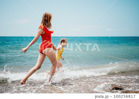 Happy loving family mother and daughter having fun together on the beach. Mum playing with her kid in holiday vacation next to the ocean - Family lifestyle and love concept Happy loving family mother and daughter having fun together on the beach. Mum playing with her kid in holiday vacation next to the ocean - Family lifestyle and love concept 100256817