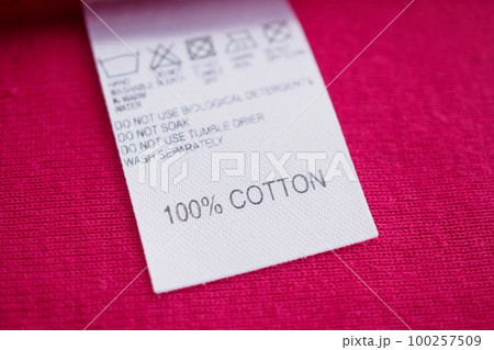 White laundry care washing instructions clothes label on red cotton shirt White laundry care washing instructions clothes label on red cotton shirt 100257509