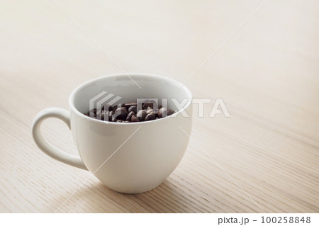 fresh roasted coffee beans in white cup on wood table 100258848